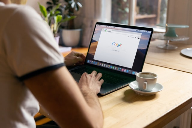 Alt-tag: Photo of a man from behind sitting and using a laptop to do a Google search as a featured image for a post about ways to get your WordPress website indexed by Google