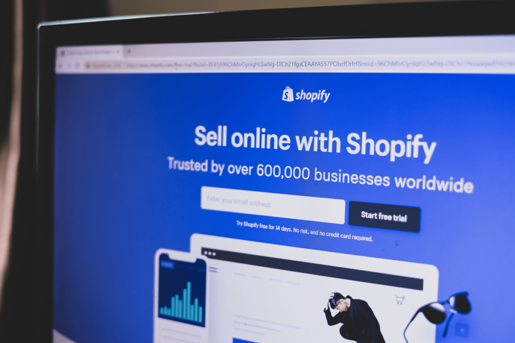 A laptop with shopify's homepage projected on its screen
