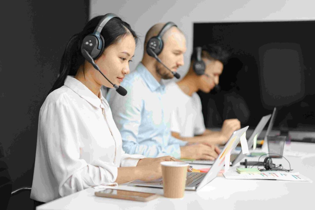 Customer support agents with headsets and laptops